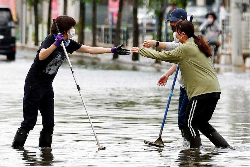 Residents reach out hands each other on a flooded road in Kurume city, Fukuoka prefecture, southern Japan.