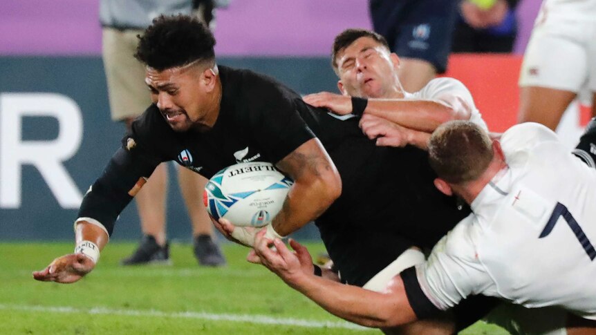A New Zealand All Blacks player dives over the goal line with the ball under his left arm to score a try against England.