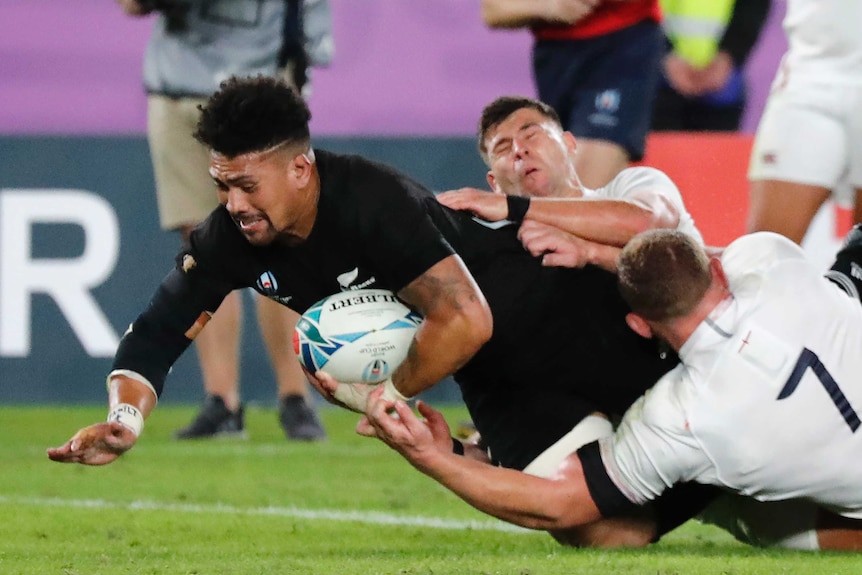 A New Zealand All Blacks player dives over the goal line with the ball under his left arm to score a try against England.