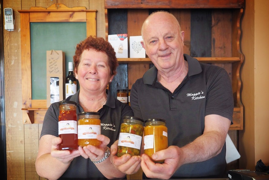 Russell and Maggie hold jars of their pickles and relishes.