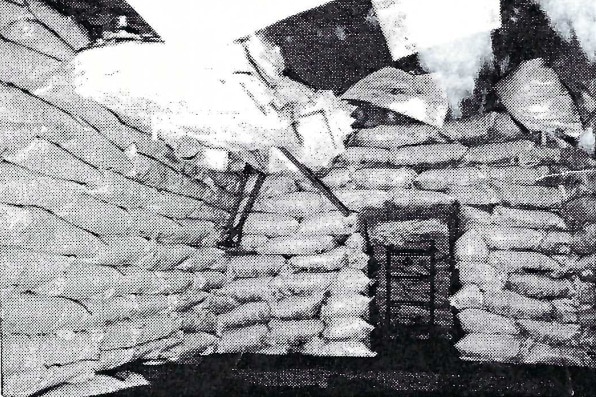 A black and white photo of a makeshift bunker built with sand bags