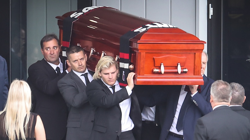 Men carry a casket to a hearse