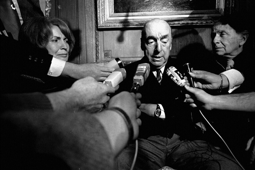 Chilean poet Pablo Neruda being surrounded by reporters with microphones in his face