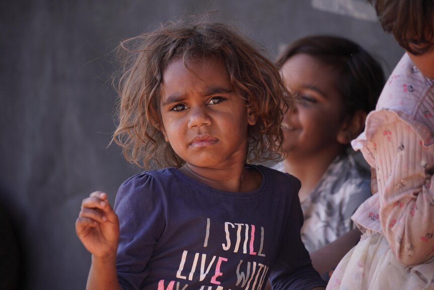 A young Aboriginal girl sits with other girls 