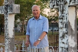 A photo of historian Peter Forrest between two graves, looking at the camera.
