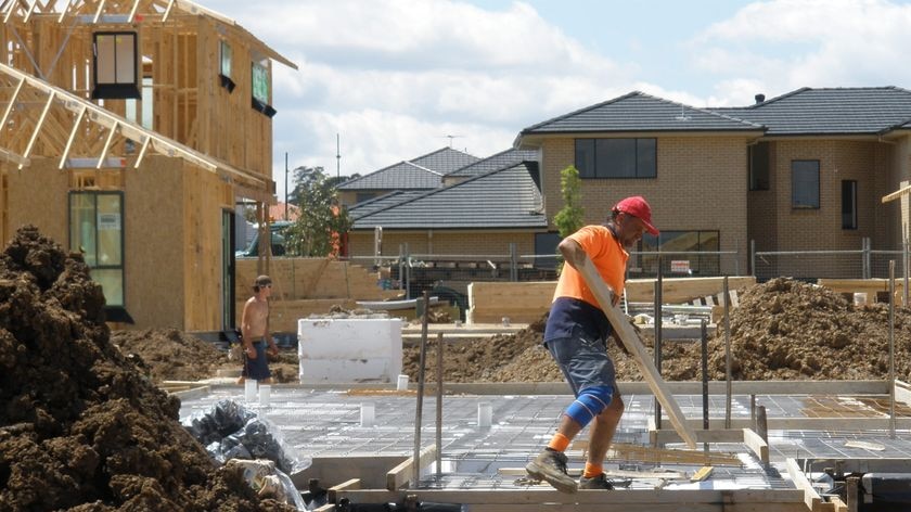 A worker carries a plank of wood on a construction site in north-west Sydney