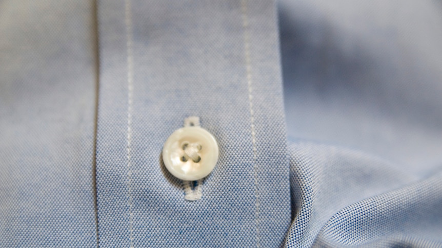 Close-up of a man's shirt showing placket and button.