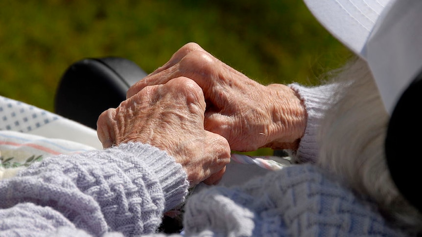 Close up photo of an elderly person's hands as they sit in a wheelchair