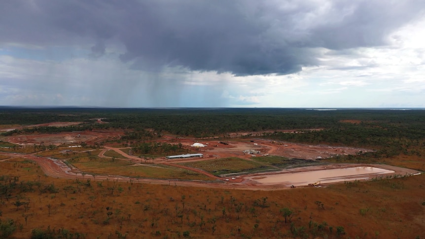 An aerial photo of a large landscape, with red dirt. The some cleared areas and roads can be seen.