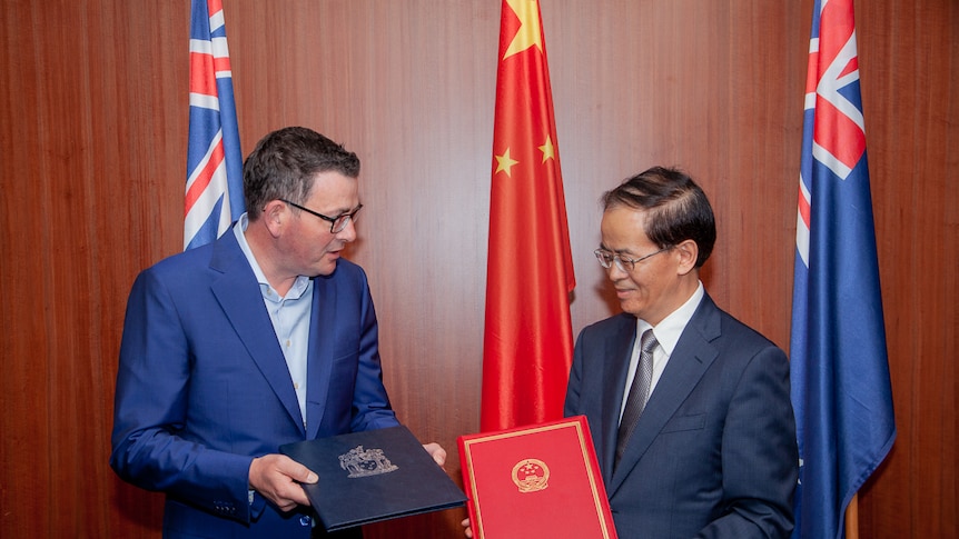 Premier Daniel Andrews and Chinese ambassador to Australia Cheng Jingye in Melbourne who are both holding compendiums.