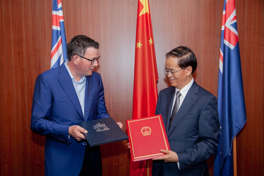 Premier Daniel Andrews and Chinese Ambassador to Australia Cheng Jingye in Melbourne who are both holding compendiums.