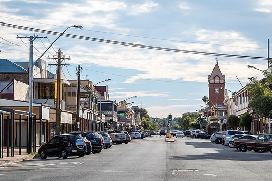 Broken Hill's main street, with cars and businesses on both sides and a clocktower in the distance.