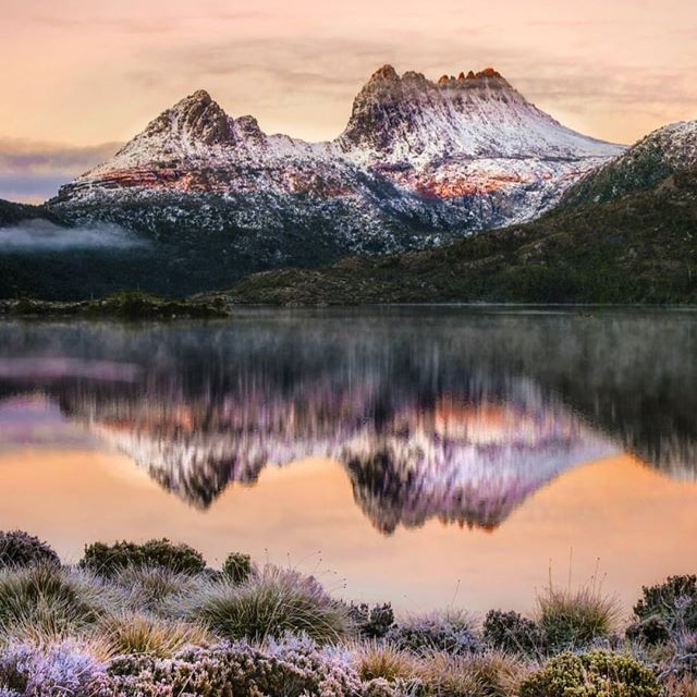 Snow-topped mountain reflected in lake at sunrise