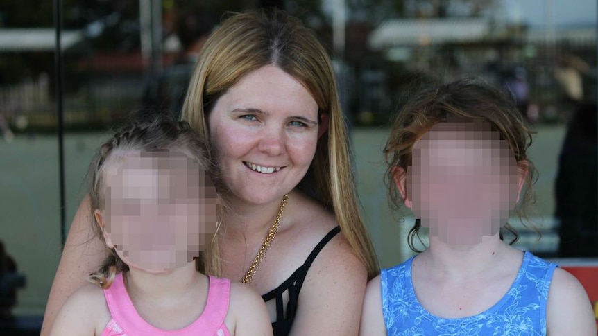 A lady pictured with two children, their faces blurred out.