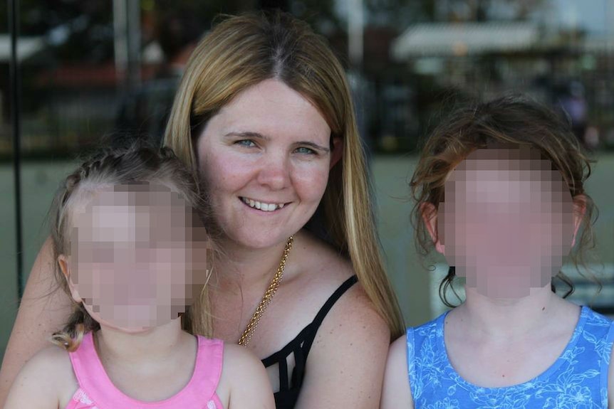 A lady pictured with two children, their faces blurred out.