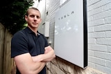 a man outside a house with a tesla