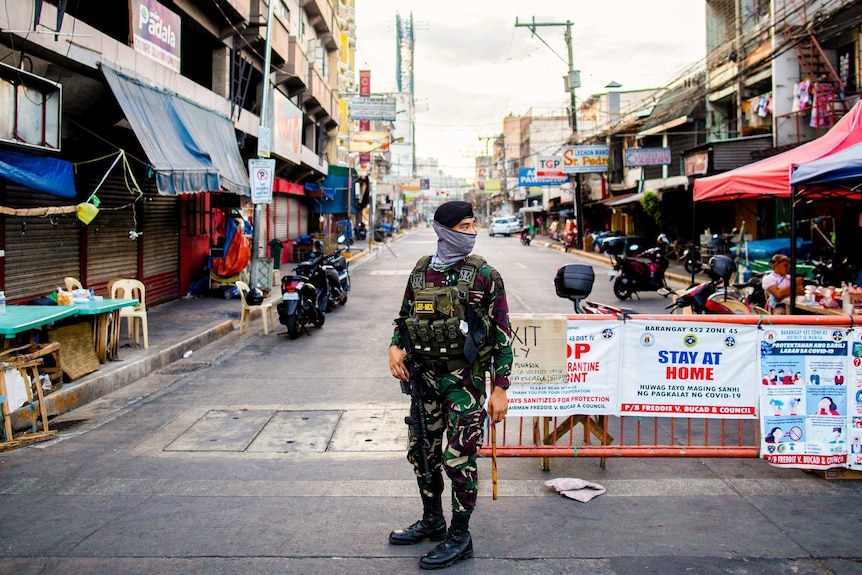 A soldier stands at a road block in Manila in a face mask