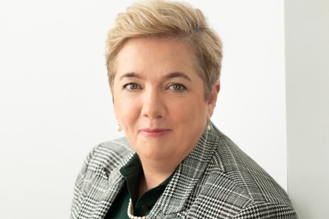 A woman with short blonde hair looks at camera