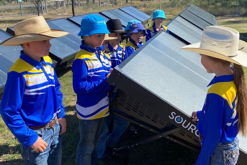 A group of young school children inspecting large solar powered hydropanels.