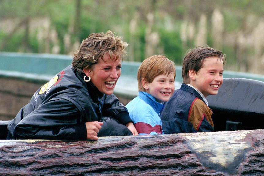 A blonde woman sits on a ride with a little redheaded boy and a blonde boy