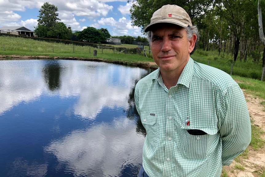 A man looks concerned standing in front of water.