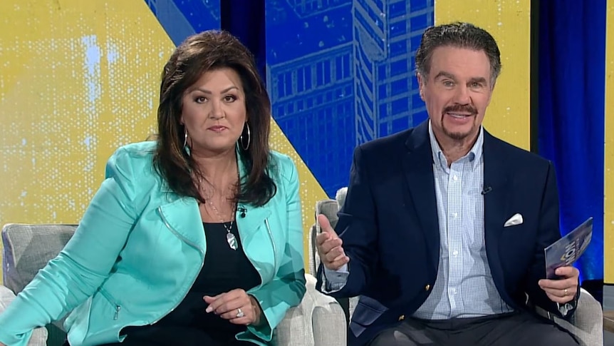 Joni and Marcus Lamb sitting on a TV couch speaking to the camera.