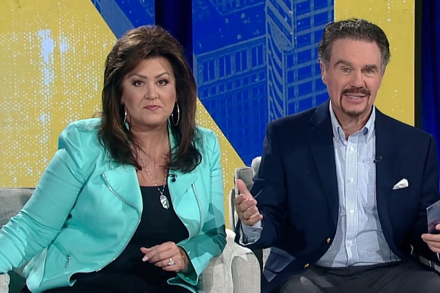 Joni and Marcus Lamb sitting on a TV couch speaking to the camera.