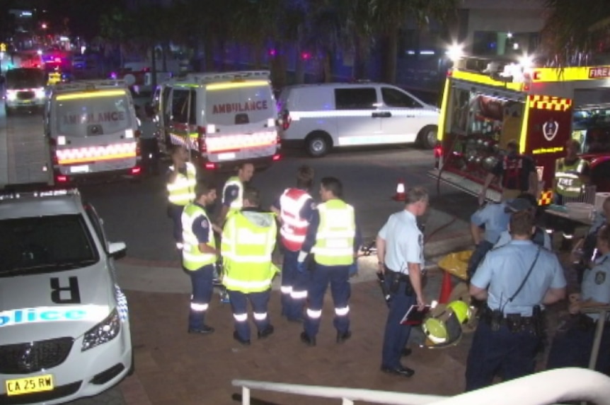 Two ambulances, a fire car, a police car and emergency service workers gather in a street.