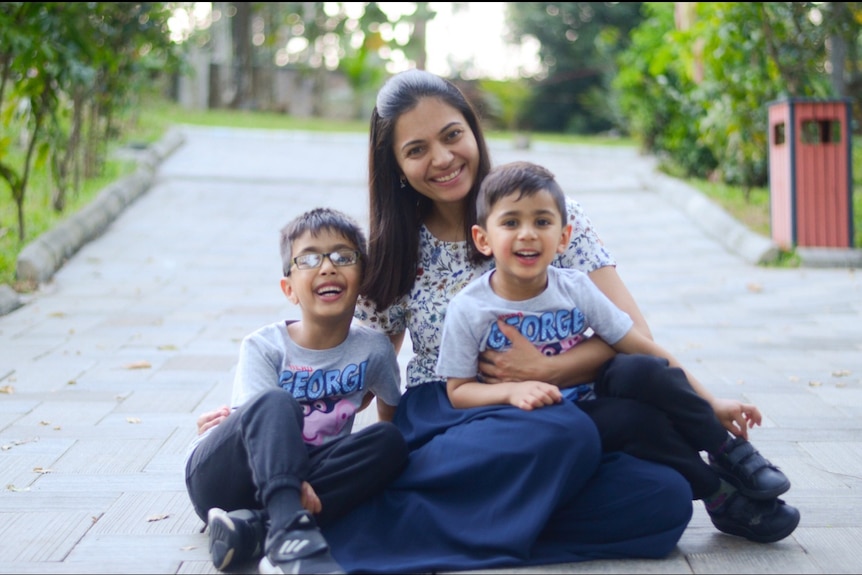 A mother with two sons sitting.