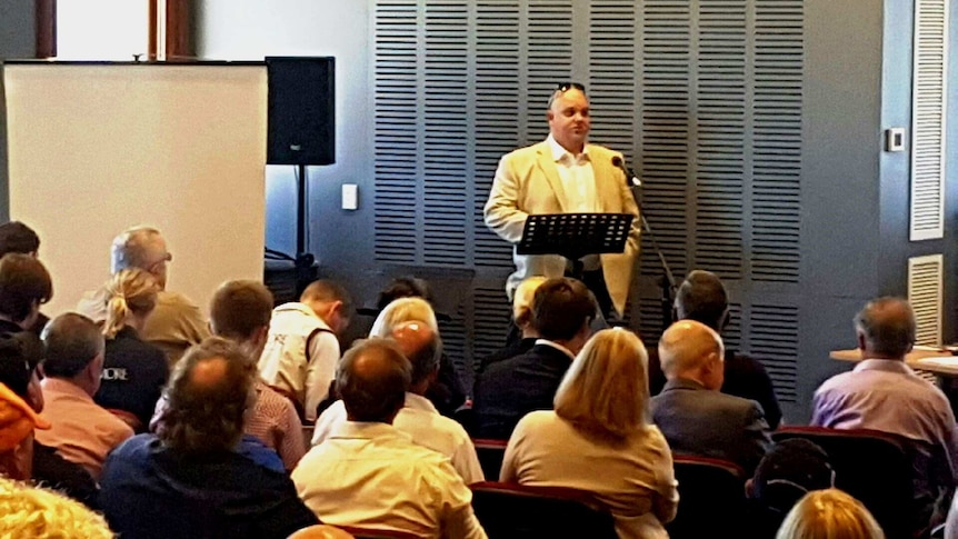 Nathan Tinkler addressing a crowded room of people.