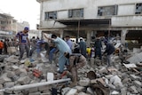 People and paramilitary personnel clear the rubble after a blast in an industrial area in Karachi.