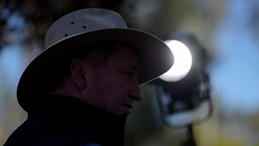Barnaby Joyce is in shadow while a spotlight behind him points towards him. The light is out of focus.