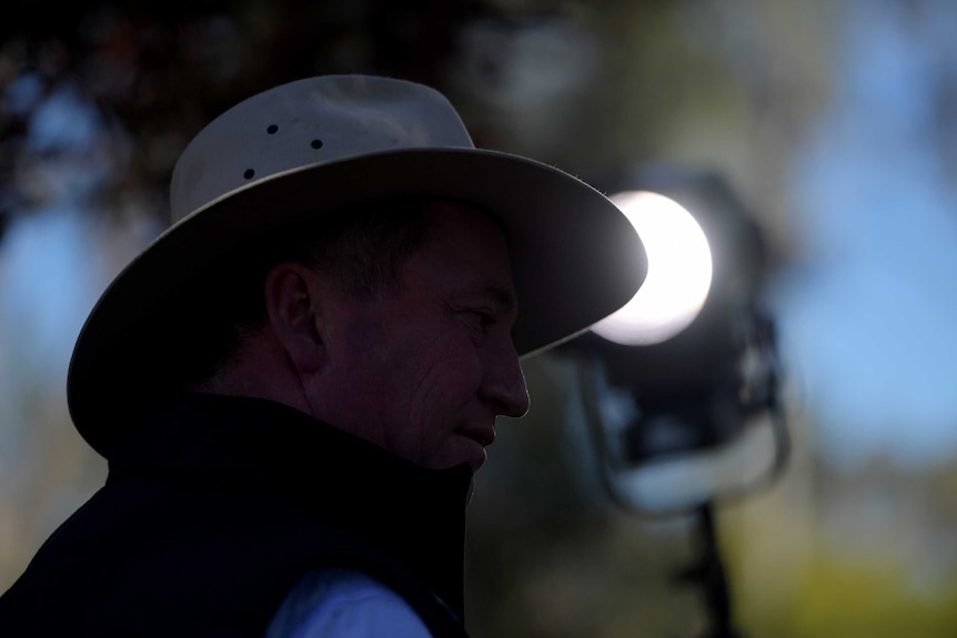 Barnaby Joyce is in shadow while a spotlight behind him points towards him. The light is out of focus.