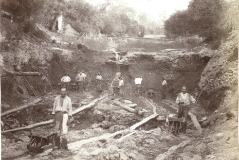 Miners pictured, in black and white, working in a gully.