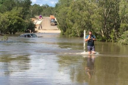 A police officer with two dogs rescued from the bonnet of a car stuck in a flooded Archer River