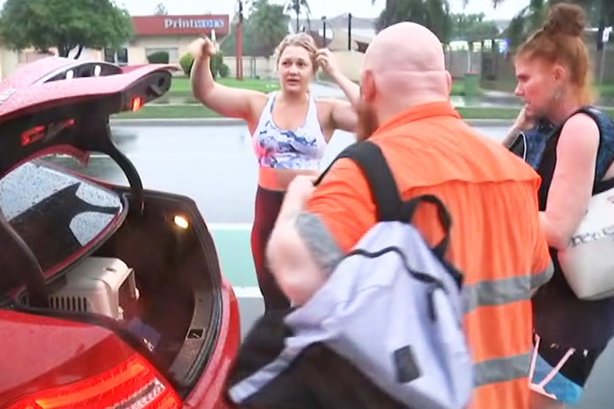 Two people place their bags in the boot of a woman's car