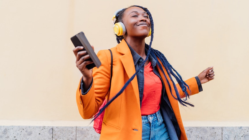 Woman smiles with eyes closed, listening on headphones