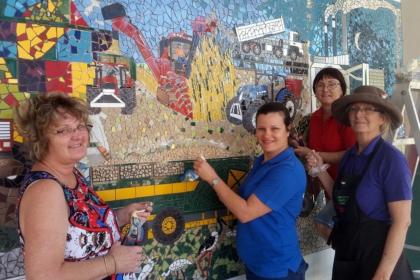 Volunteers use tools to finish tiling the Mercer Lane Mosaic.