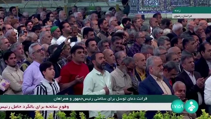 A video screenshot shows a large crowd praying.