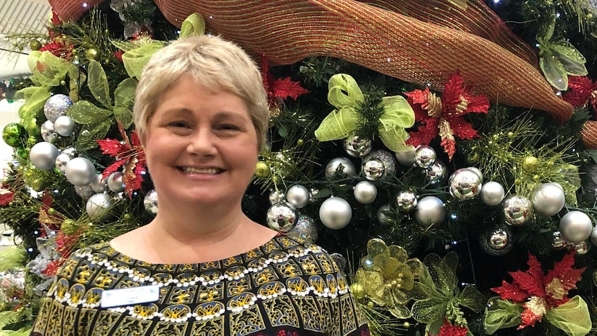 Woman stands in front of Christmas Tree