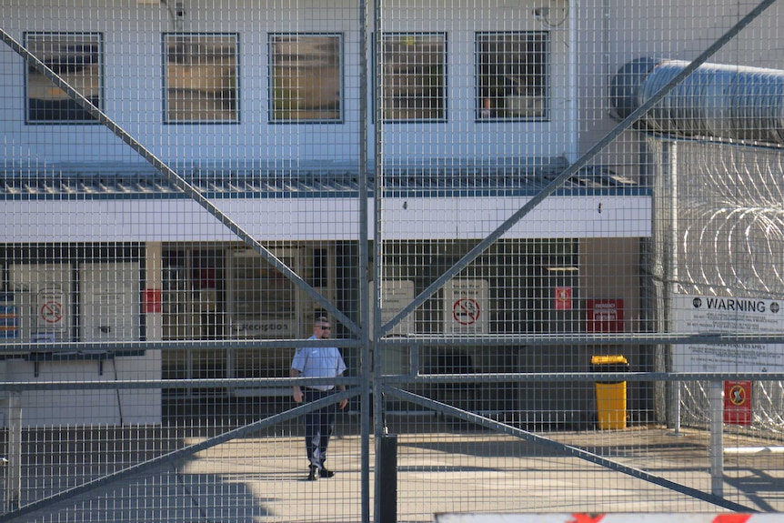 A guard stands behind the entrance to Borallon Training and Correctional Centre in Ironbark