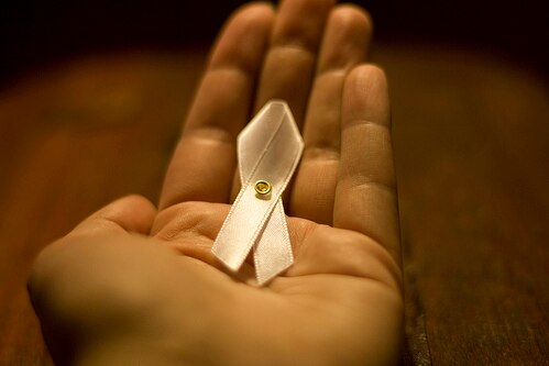 A hand hold a white ribbon for White Ribbon Day.