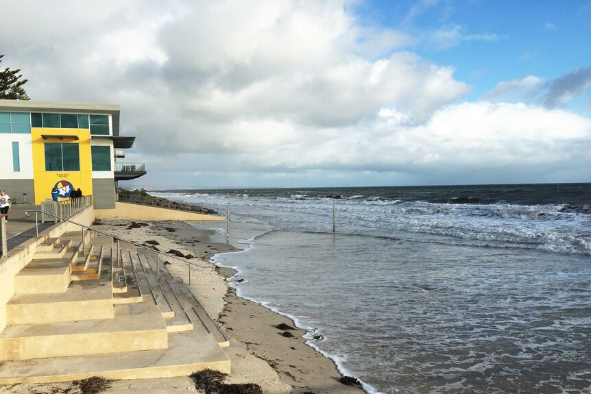 High tide covers the often wide sandy beach at Henley Beach