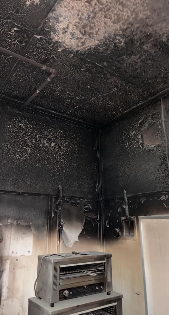 Blackened walls above a cooker in a burnt-out kitchen.