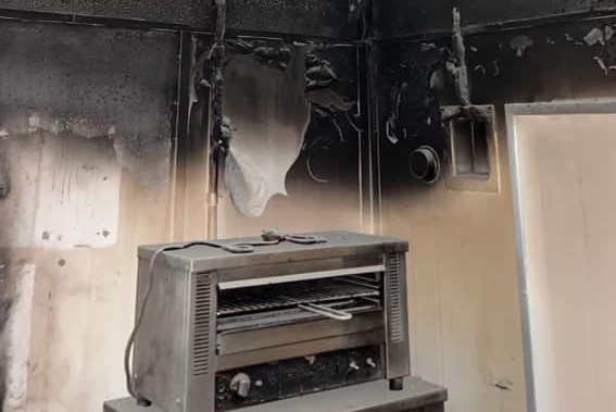 Blackened walls above a cooker in a burnt-out kitchen.