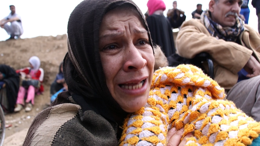 A woman holding a baby cries