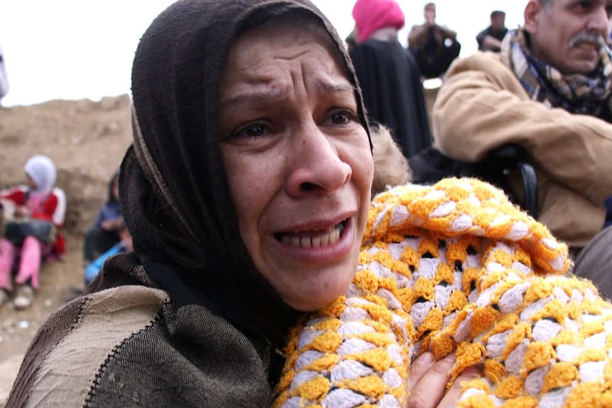 A woman holding a baby cries