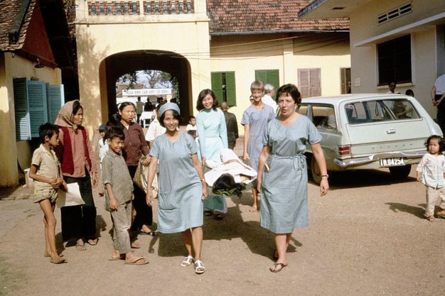 Four female nurses carry a stretcher.