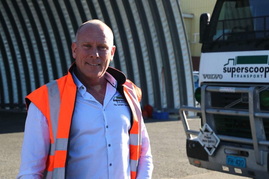 Adam Williams standing in his truck yard, in front of a truck.