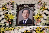 A framed photo of a man surrounded by flowers.